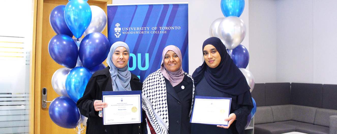 Three students holding up diplomas at the Academic Bridging Program graduation.