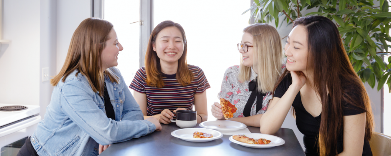 Four residents eating pizza on the kitchen island in their suite.