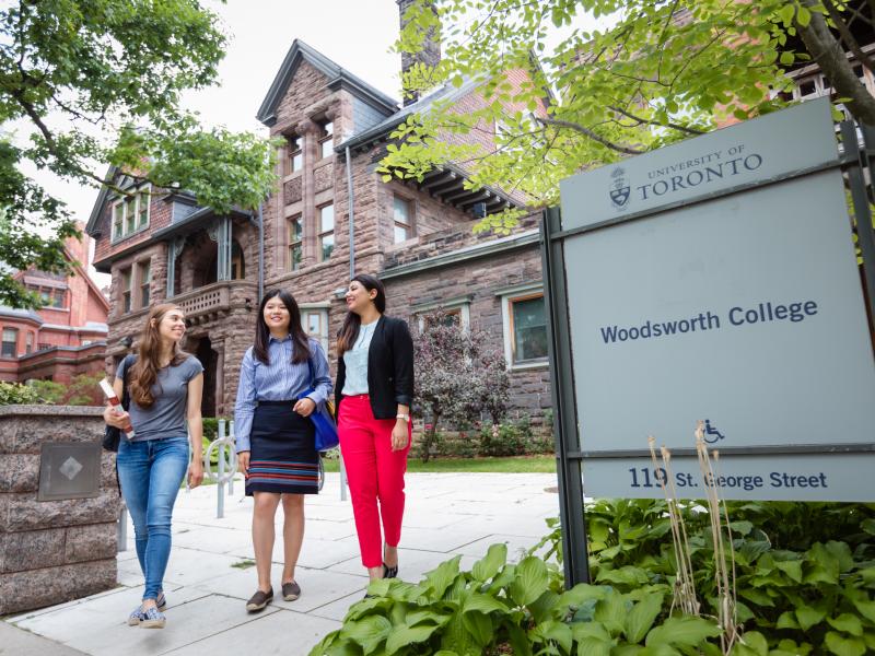 Three students walking in front of Woodsworth sign
