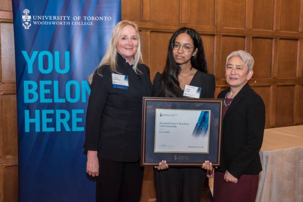 Layan (middle) stands with Lynda Hamilton (left) and Principal Chin (right), holding her award certificate.