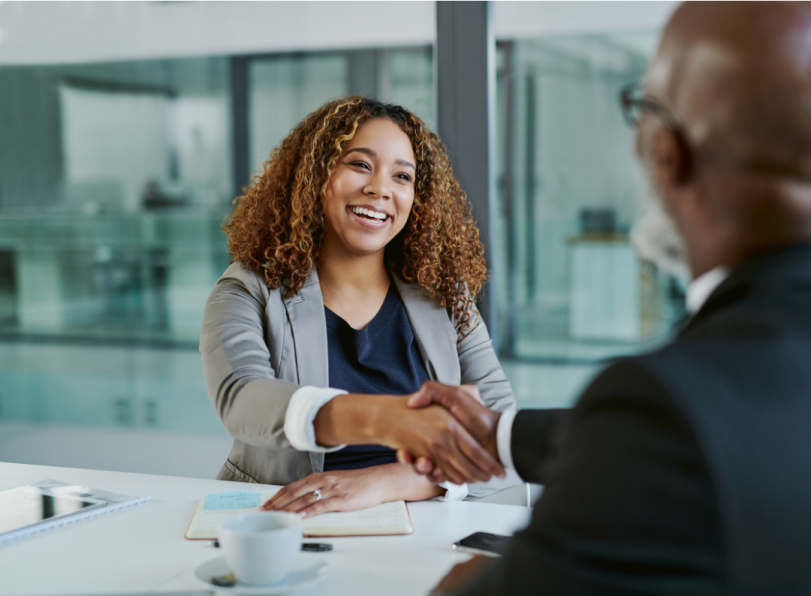 Image of woman shaking someone's hand across a table.
